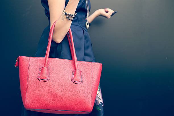 Fashionable beautiful big red handbag Fashionable beautiful big red handbag on the arm of the girl in a fashionable black dress, posing near the wall on a warm summer night. Warm color purse photos stock pictures, royalty-free photos & images