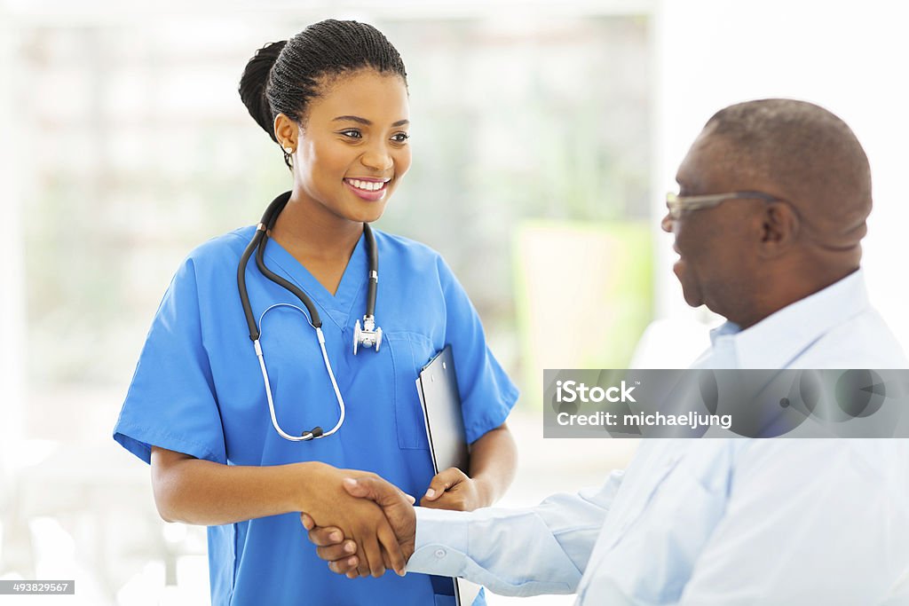 african american medical nurse handshaking with senior patient friendly african american medical nurse handshaking with senior patient Patient Stock Photo