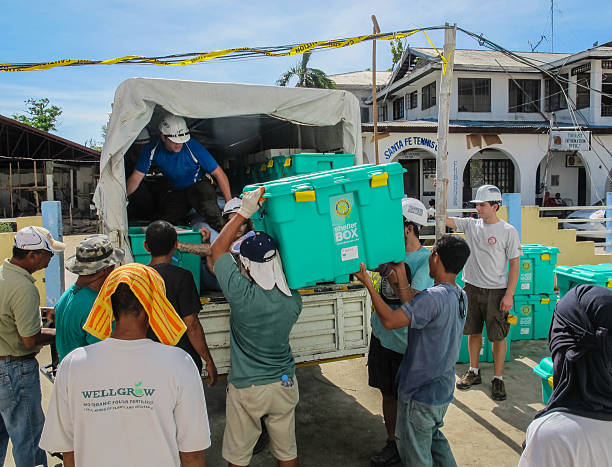 Humanitarian Aid workers loading ShelterBox tents Santa Fe,Bantayan,Philippines - December 18, 2013: Humanitarian aid workers loading ShelterBox emergency aid onto trucks after Typhoon Haiyan in the Philippines humanitarian aid stock pictures, royalty-free photos & images