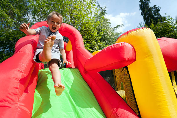 niño en tobogán inflable castillo inflable para saltar - inflatable child playground leisure games fotografías e imágenes de stock
