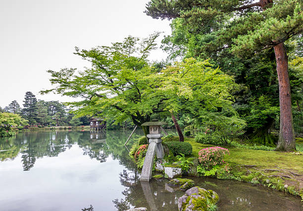 japanese garden with stone lantern and big mossy rock stock photo