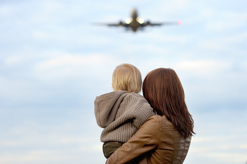 Mujer agarrando niño pequeño con avión en el fondo photo