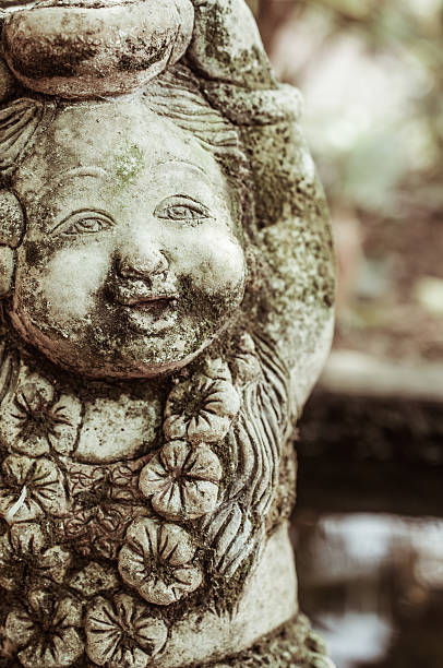 Savannah, GA, USA; September 08, 2025: A bronze statue depicts a child joyfully splashing water in a vibrant garden in Savannah, Georgia, with colorful plants and decor.