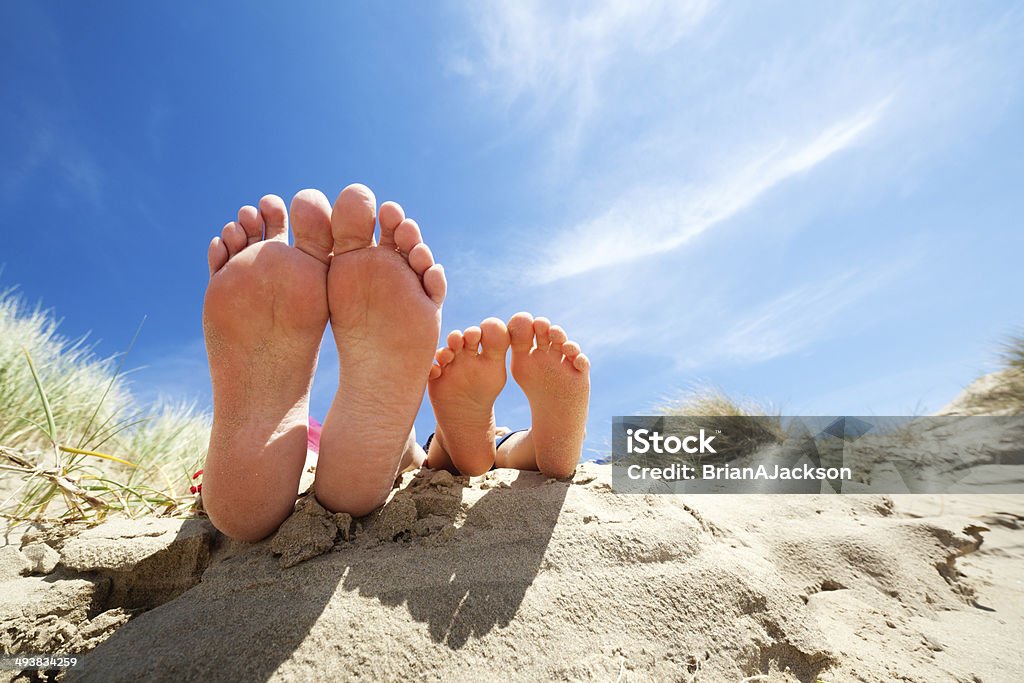 Relaxing feet on the beach Family feet relaxing and sunbathing on the beach concept for vacation and summer holiday Beach Stock Photo