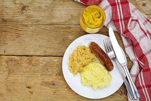 Bratwurst with sauerkraut mashed potatoes and mustard on a rustic wooden table, view from above, copy space
