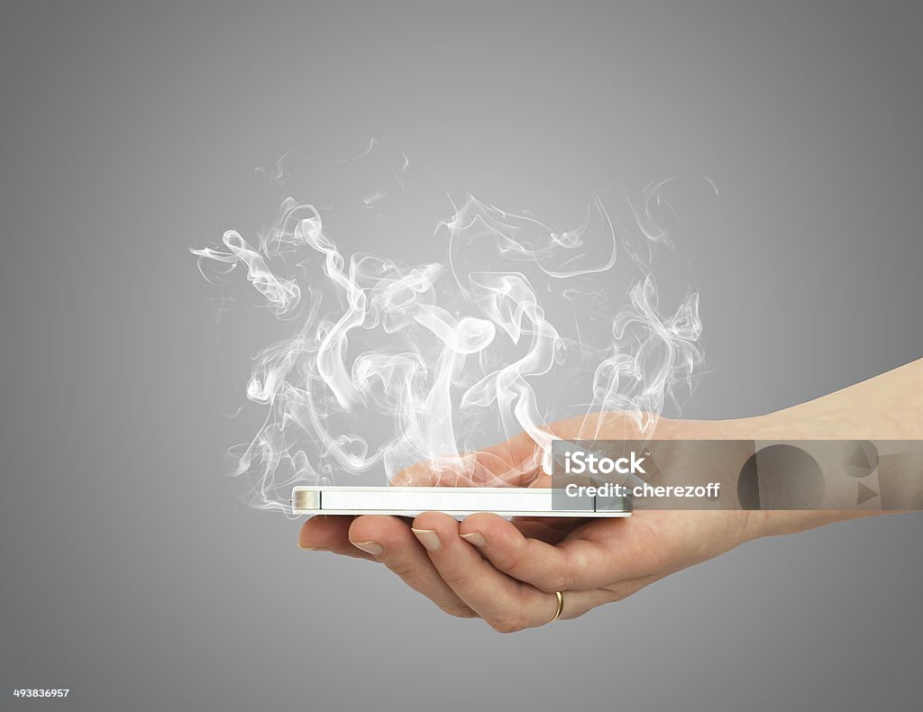 Hand holding smart phone with white smoke Hand holding smart phone with white smoke. The technology concept Smoke - Physical Structure Stock Photo