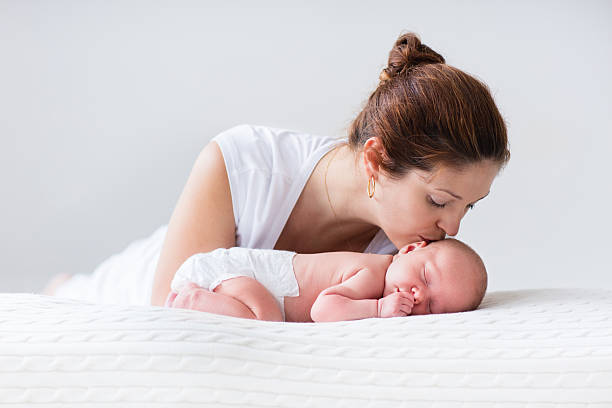 jovem mãe e bebê recém-nascido em branco quarto - mother new baby nursery - fotografias e filmes do acervo