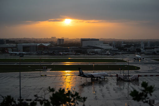 Sydney Australia April  17, 2015  Airbus A320 in Air New Zealand colour scheme arriving at Sunrise at Kingsford Smith airport. Also visible some ground grew trucks, and some Commercial Airplanes parked, waiting for passengers to board.  