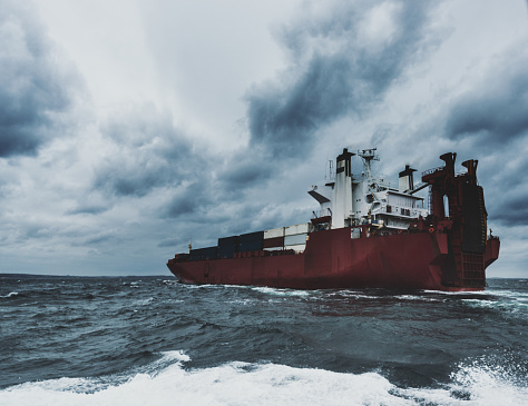 A sea level view of a container ship in the North Atlantic under dramatic skies.