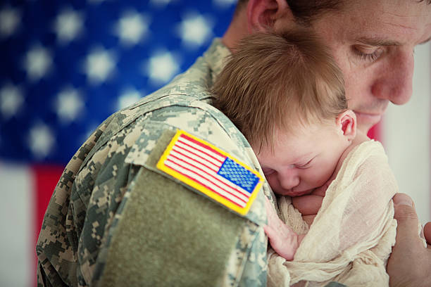 American soldier holding newborn baby stock photo