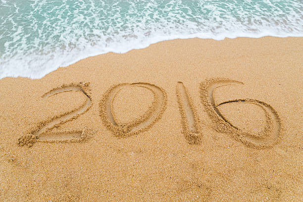 istock year 2016 inscription written on sandy beach with wave approaching 493856634