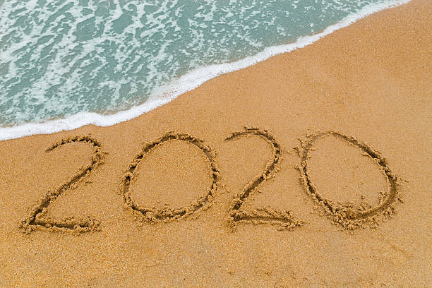 istock year 2020 inscription written on sandy beach with wave approaching 493856824