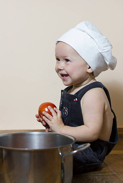 istock Little happy boy chef with red tomato 493859372
