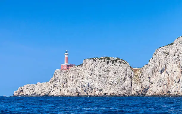 Punta Carena. Red lighthouse tower stands on the rocky coast of Capri, Italy