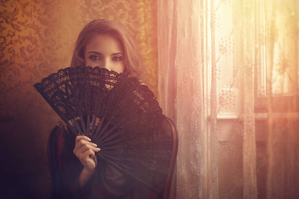 istock young woman hiding behind a lace fan 493885011