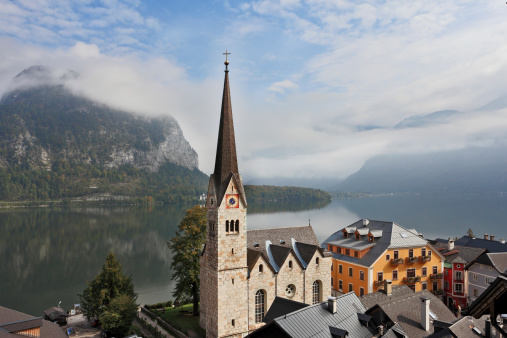 The most picturesque small town in Austria - Hallstatt. Slender belfry and Lutheran church on the shore of Lake Hallstatt. On the opposite shore of the lake - the beautiful mountains overgrown with forests.