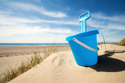 Childs bucket and spade or sand pail and shovel at the beach on a sunny summer day