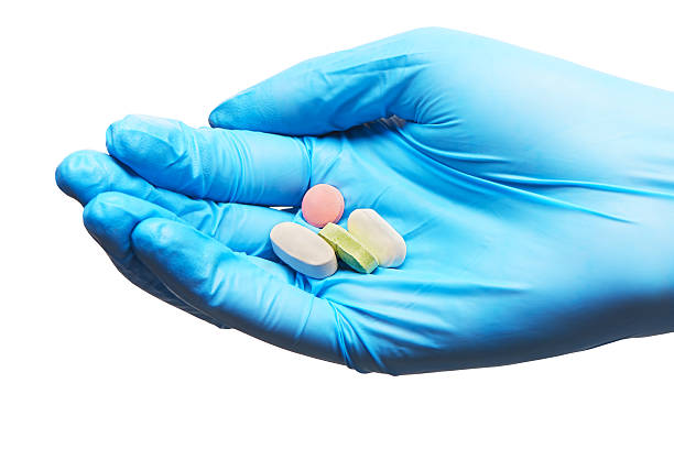 gros plan de la main sur une tablette de médecin en paire de gants bleus - surgical glove human hand holding capsule photos et images de collection
