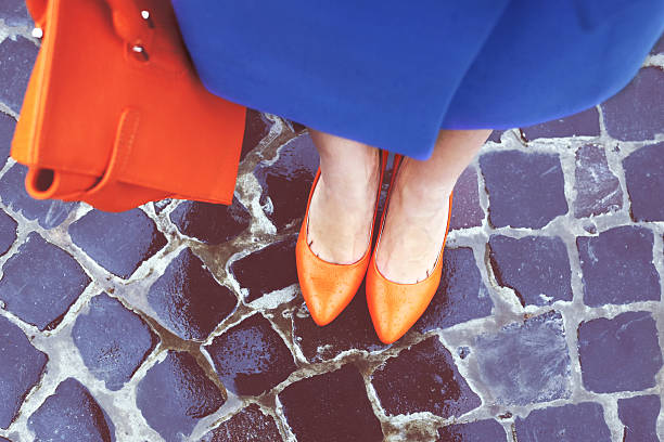 Shoes and bag Women's legs in orange shoes. Bright orange shoes and bag. Blue coat, orange classic ladies shoes and tote bag. Rainy day. Street fashion. Street style. Business casual look. Autumn outfit. dress shoe photos stock pictures, royalty-free photos & images