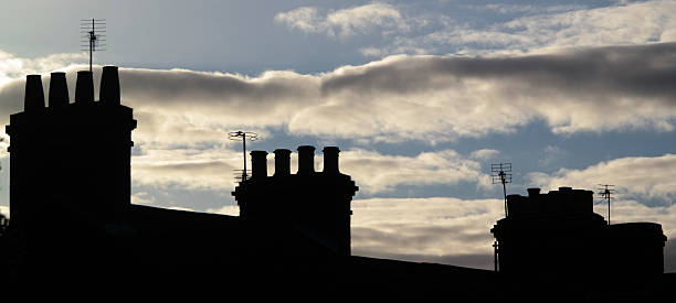 istock Three roof top chimneys in sunlit cloudy sky. 493889530