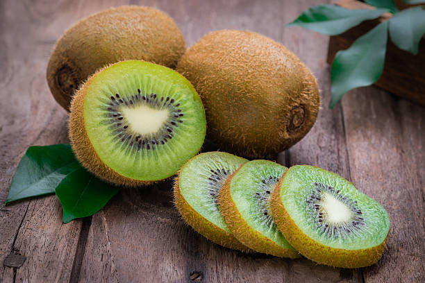 Kiwi fruit slices on wooden table Kiwi fruit slices on wooden table kiwi fruit stock pictures, royalty-free photos & images