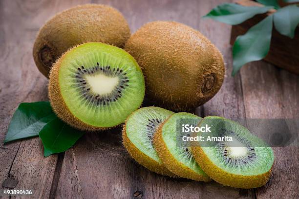 Kiwi Fruit Slices On Wooden Table Stock Photo - Download Image Now - Kiwi Fruit, Green Color, Leaf