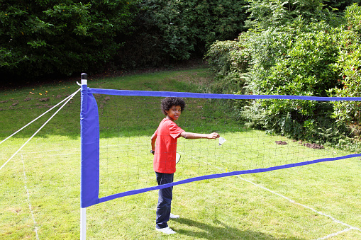 young teen playing badmington in his back garden