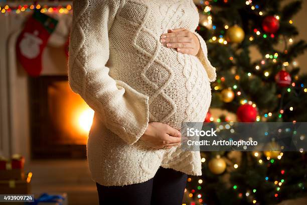 Pregnant Woman Posing Against Fireplace And Christmas Tree Stock Photo - Download Image Now