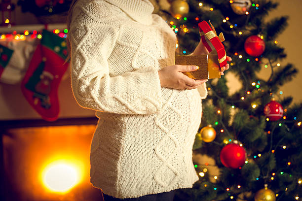 Toned shot of pregnant woman posing with Christmas gift box Toned photo of pregnant woman posing with Christmas gift box cute pregnant woman with gift stock pictures, royalty-free photos & images