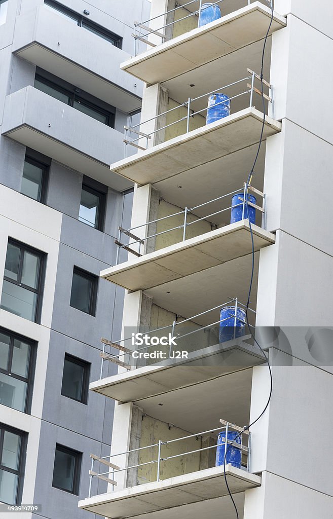building under construction concrete building under construction with safety guard rails and blue cans with another building finished Apartment Stock Photo
