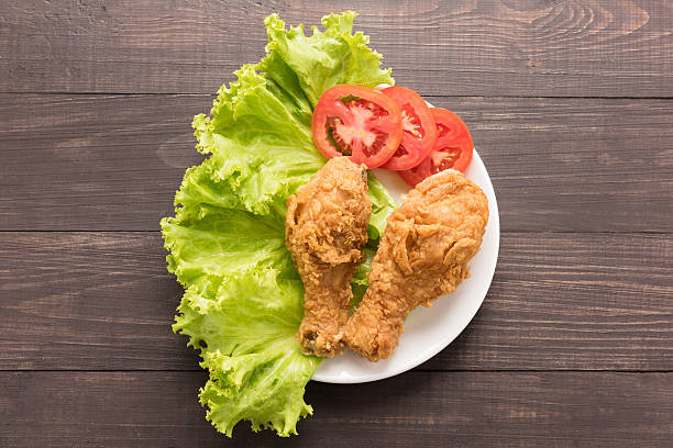 istock fried chicken drumstick with tomato on wooden background 493914940