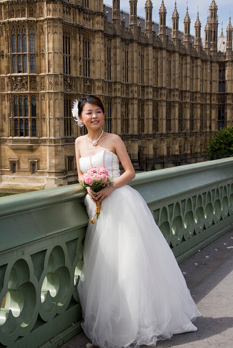 London, UK - July 25, 2011: Japanese bride with flowers in her hand poses on Westminster Bridge on July 25, 2011 in London, UK