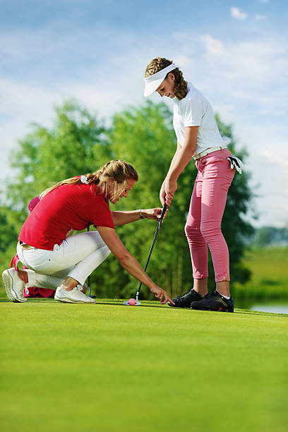 istock Trainer works with children at golf school 493916774