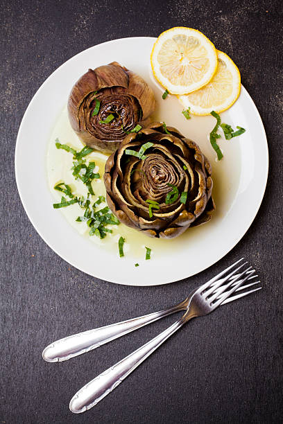 gefüllte artischocken auf einer platte mit zitrone - artichoke artichoke heart salad portion stock-fotos und bilder