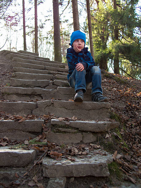 istock Boy sitting on stairs and looking into the distance 493919031
