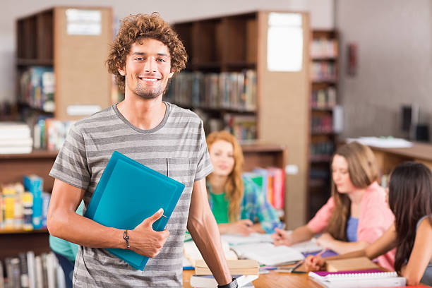 istock Student smiling with friends in background at library 493921841