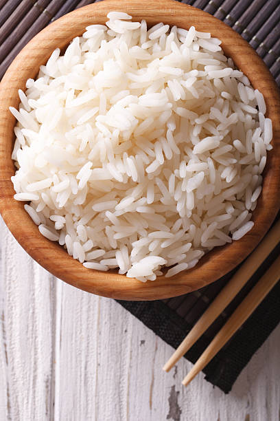 istock Asian food: rice in wooden bowl closeup. vertical top view 493930874