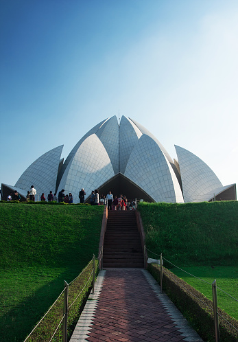 New Delhi. India- April 3, 2015: Group of believers visit the Lotus temple in New Delhi. The Lotus Temple, located in New Delhi, India, is a Bahá'í House of Worship completed in 1986. Notable for its flowerlike shape, it serves as the Mother Temple of the Indian subcontinent and has become a prominent attraction in the city.