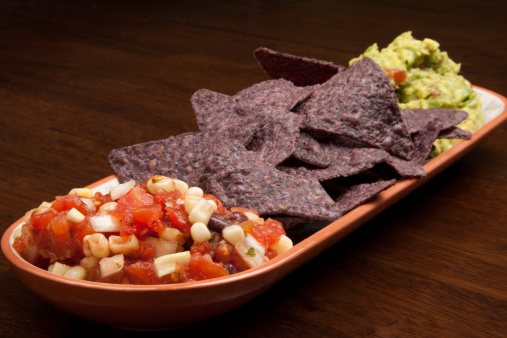 A plate of salsa, chips, and guacamole.