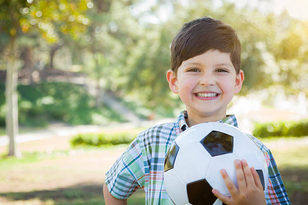 istock Cute Young Boy Playing with Soccer Ball in Park 493954523