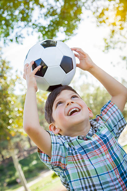 istock Cute Young Boy Playing with Soccer Ball in Park 493954759