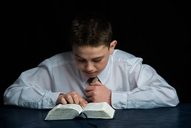 A young teen aged boy studying the scriptures