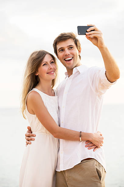 istock Couple taking a selfie on the beach at sunset 493957205