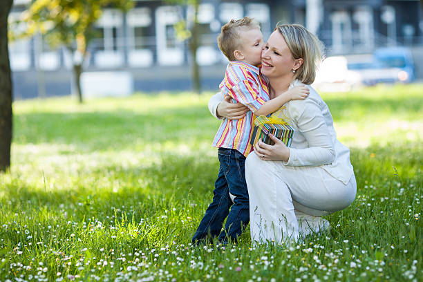Beautiful boy and mom in spring park with present stock photo