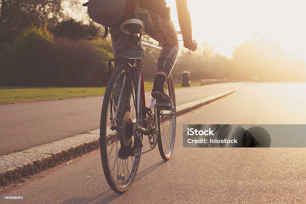 Mujer joven Ciclismo en el parque en puesta de - Foto de stock de Andar en bicicleta libre de derechos