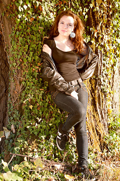 istock Beautiful smiling young woman leaning on a tree 493959911
