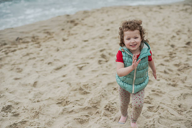 istock Little curly girl playing in the sand on seashore 493969538