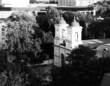 White bell towers of the Roman Catholic Church, rise above the canopy in the urban landscape of Chisinau Moldova.