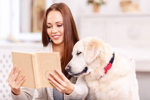 istock Young lady showing a book to her pet 493973018