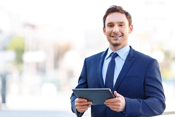 istock Grinning gentleman on balcony holding a tablet 493973942
